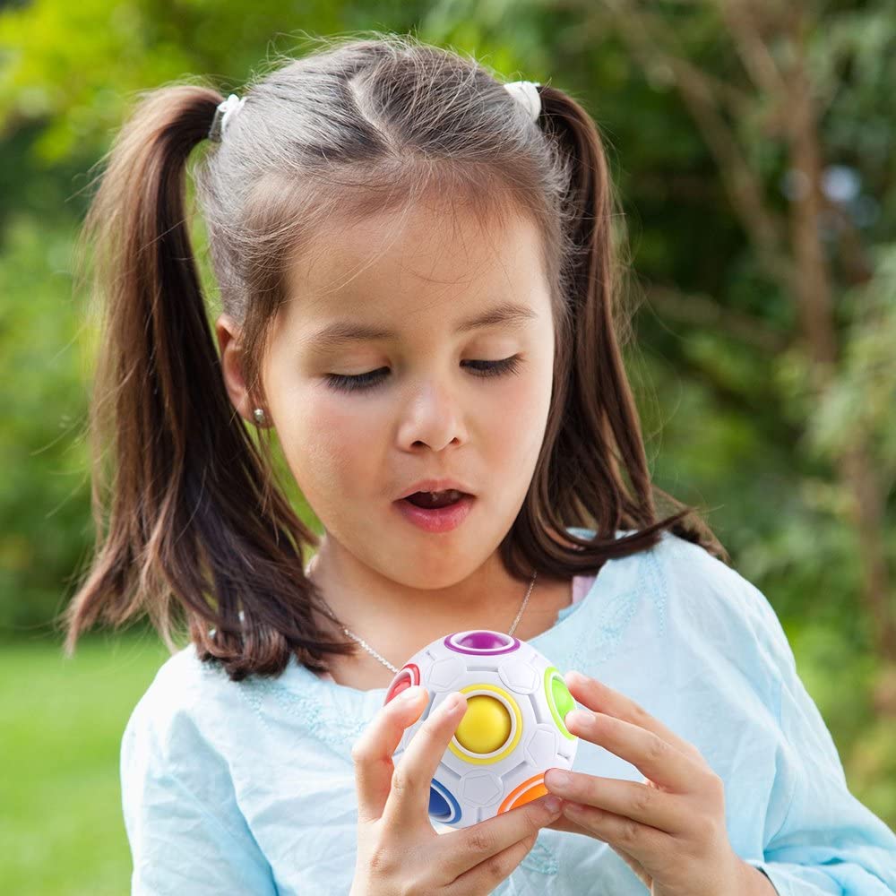 Child holding a colorful puzzle ball while playing outdoors