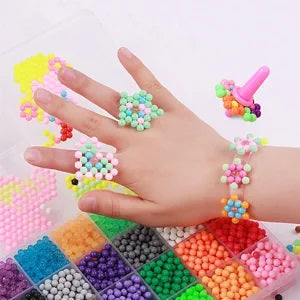 Colorful bead rings and a bracelet worn on a hand above a tray of craft beads