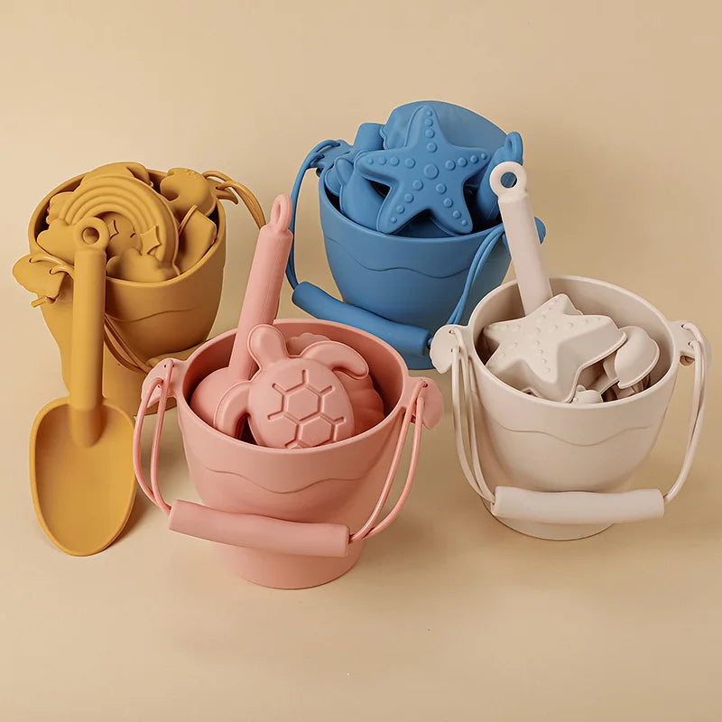 Yellow, blue, pink and beige silicone beach buckets filled with shovels and sea-themed molds.