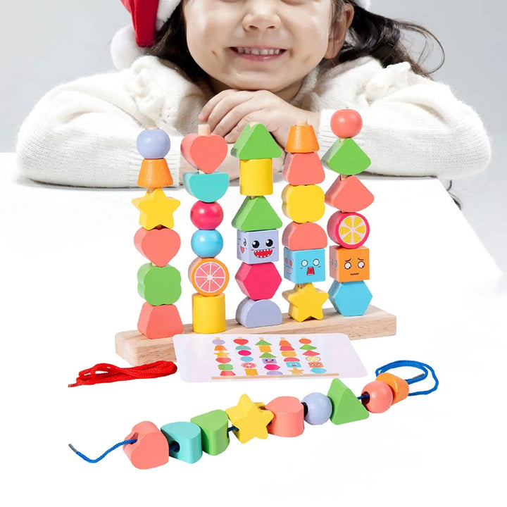 Child smiling behind a wooden stand stacked with colorful shape beads, with a pattern card and lacing cord.