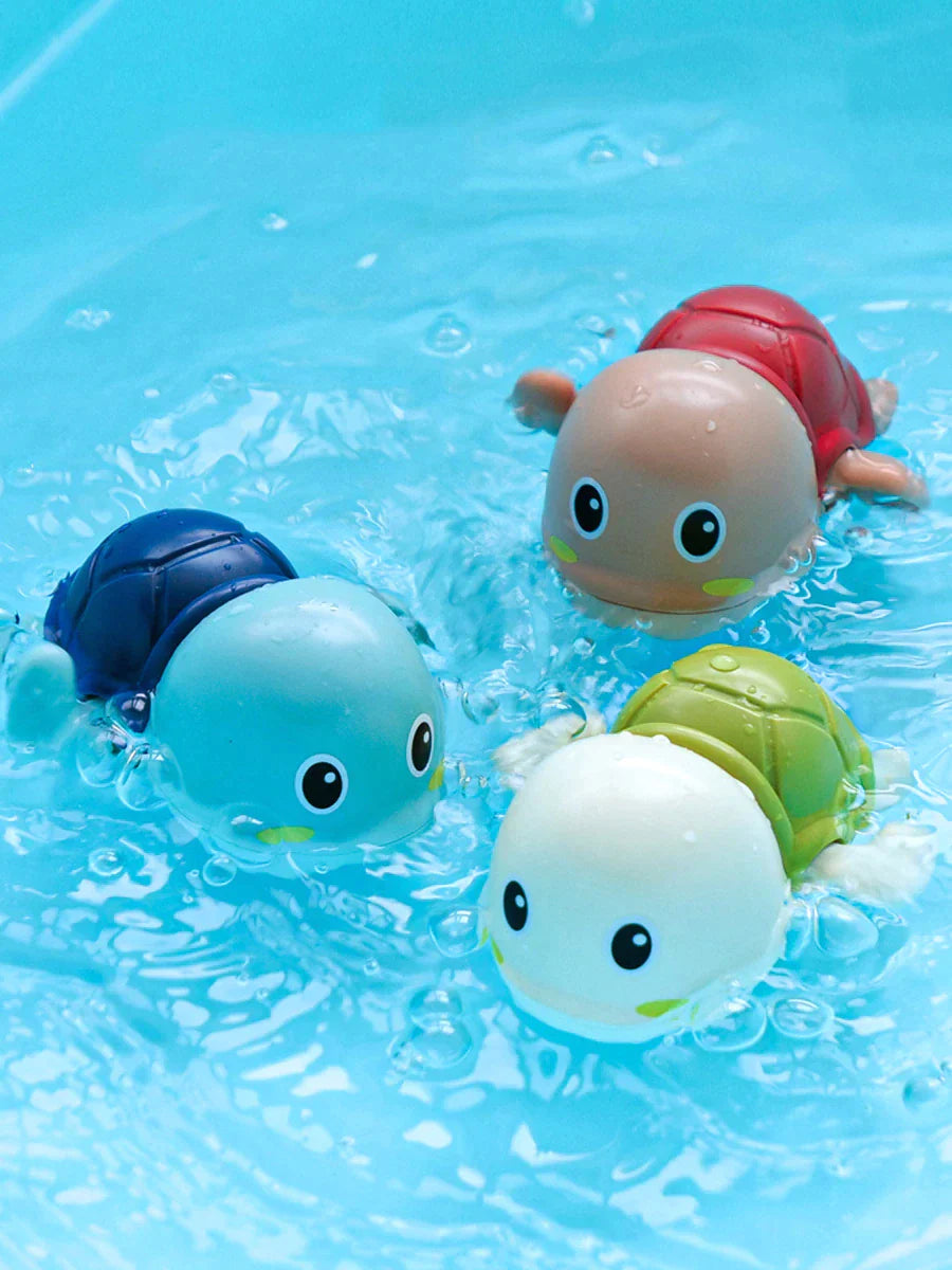 Blue, red, and green turtle bath toys swimming in clear blue water
