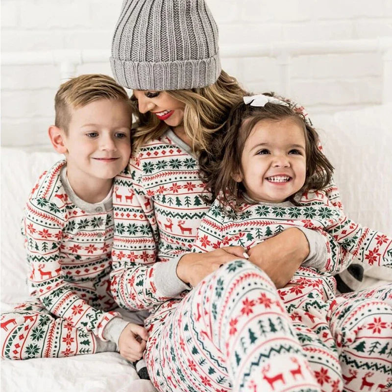 Mother in a gray knit hat sitting with two children in matching holiday pajamas