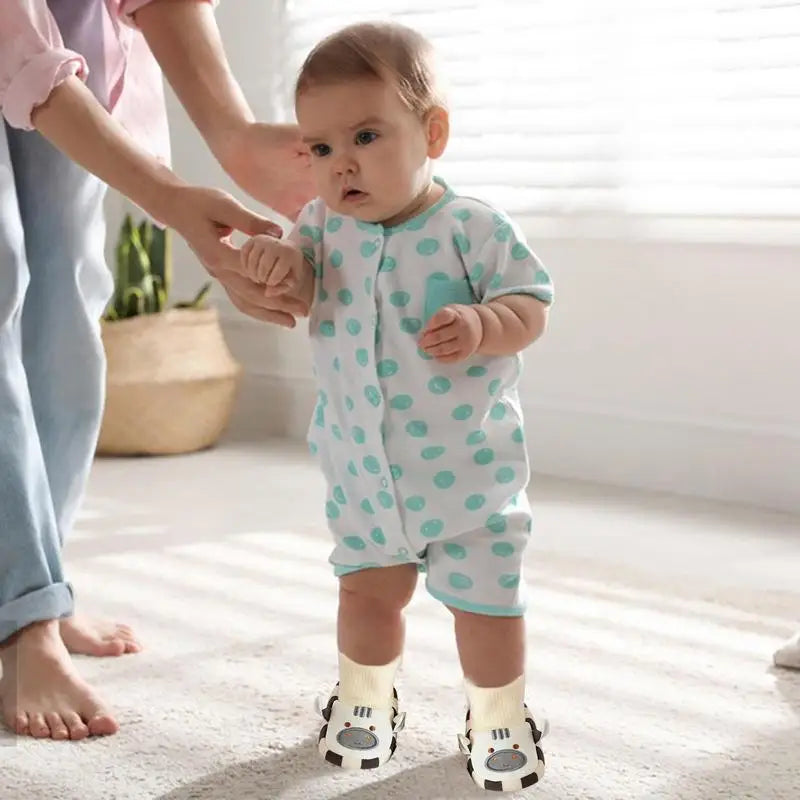 Child wearing cow indoor shoes while standing with an adult&