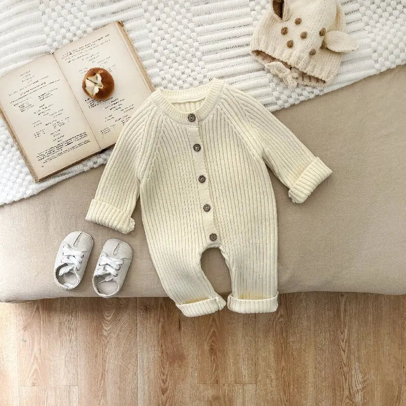 Cream ribbed baby romper laid flat with long sleeves and cuffed legs