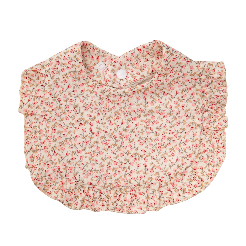 Cream cotton baby bib covered in small pink roses with a ruffled edge