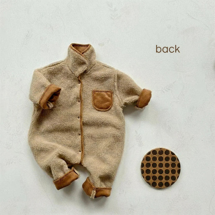 Reversible baby romper with the cream fleece side out and brown chest pocket and cuffs