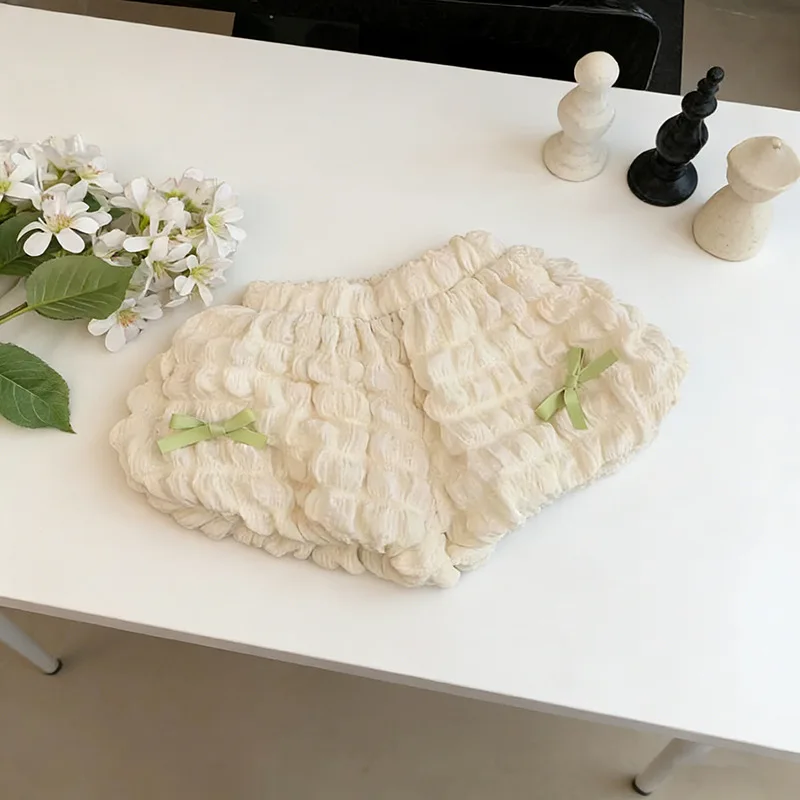 Cream ruffle shorts with green bows and an elastic waistband
