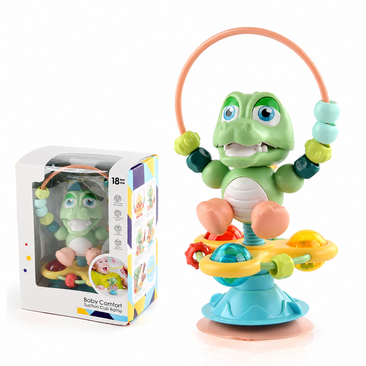 Green crocodile rattle with ball details and a beaded loop, shown beside its box
