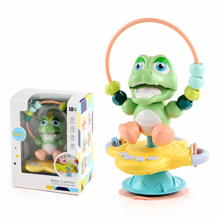 Green crocodile rattle with a bead loop and ring attachments, shown with its box