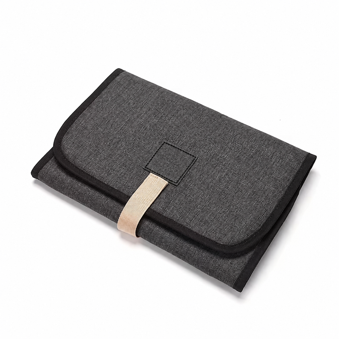 Dark gray changing mat folded with black edging and a beige strap