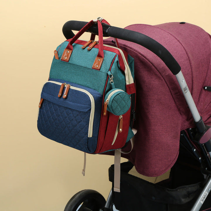 Blue-and-green diaper backpack hanging from a stroller handle