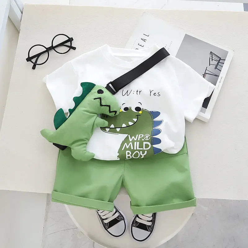 Front view of a white dinosaur-print T-shirt, green cuffed shorts and matching green dinosaur toy