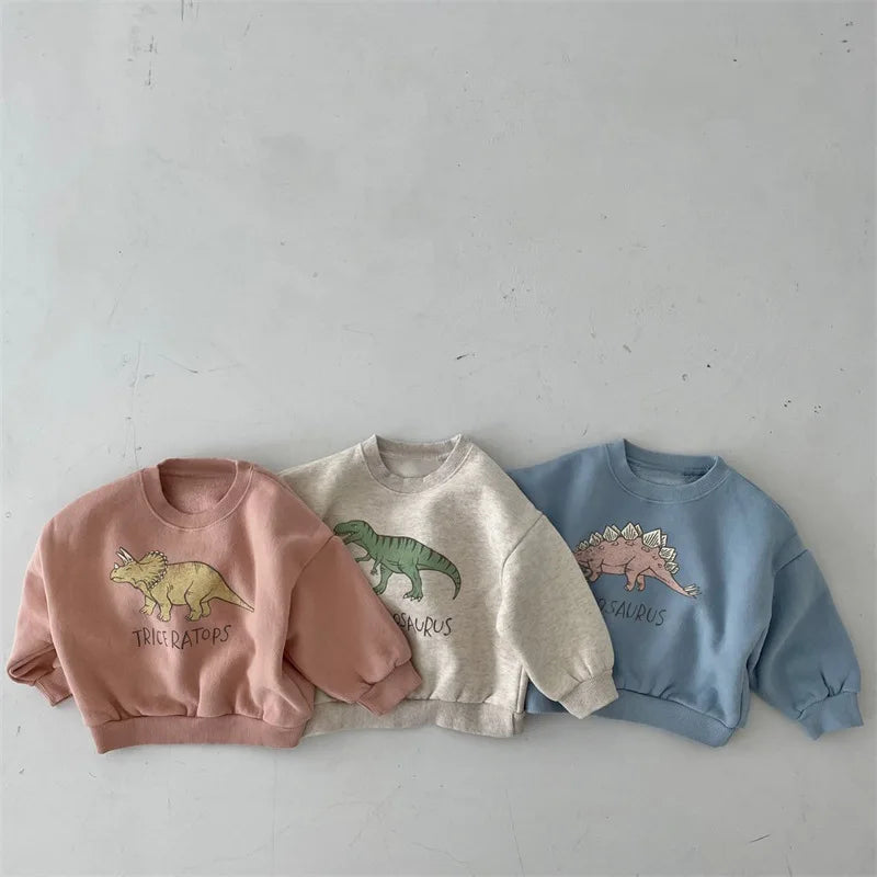 Pink, light gray and light blue children's sweatshirts with dinosaur graphics