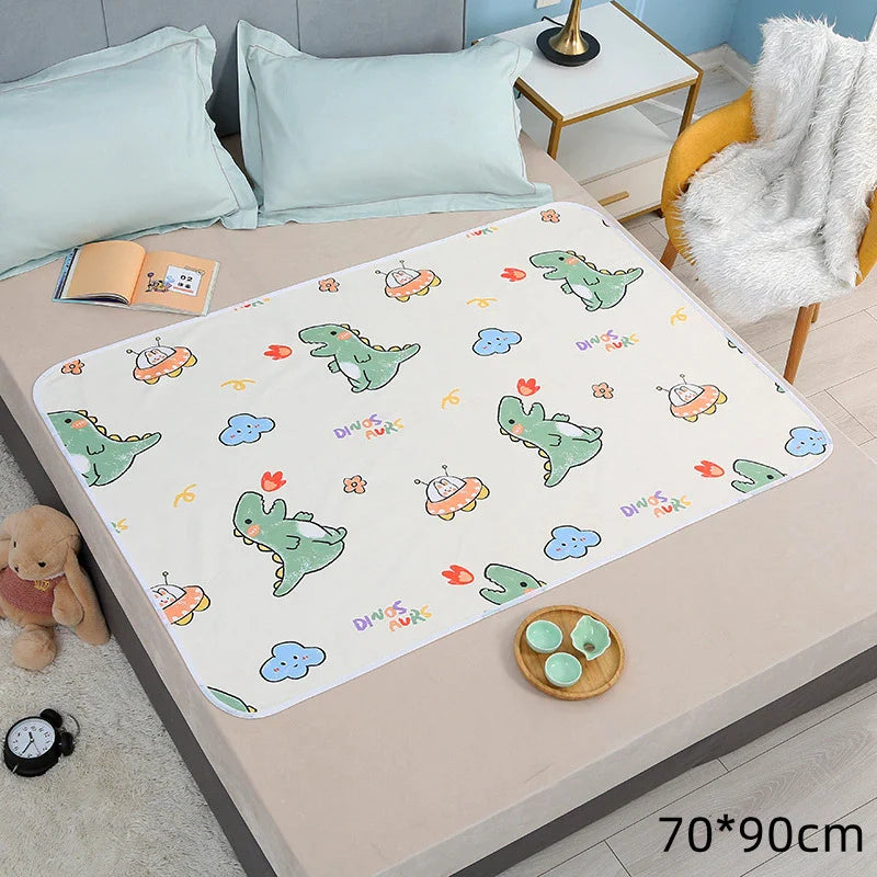 Dinosaur-print changing mat on a bed, labeled 70 x 90 cm.