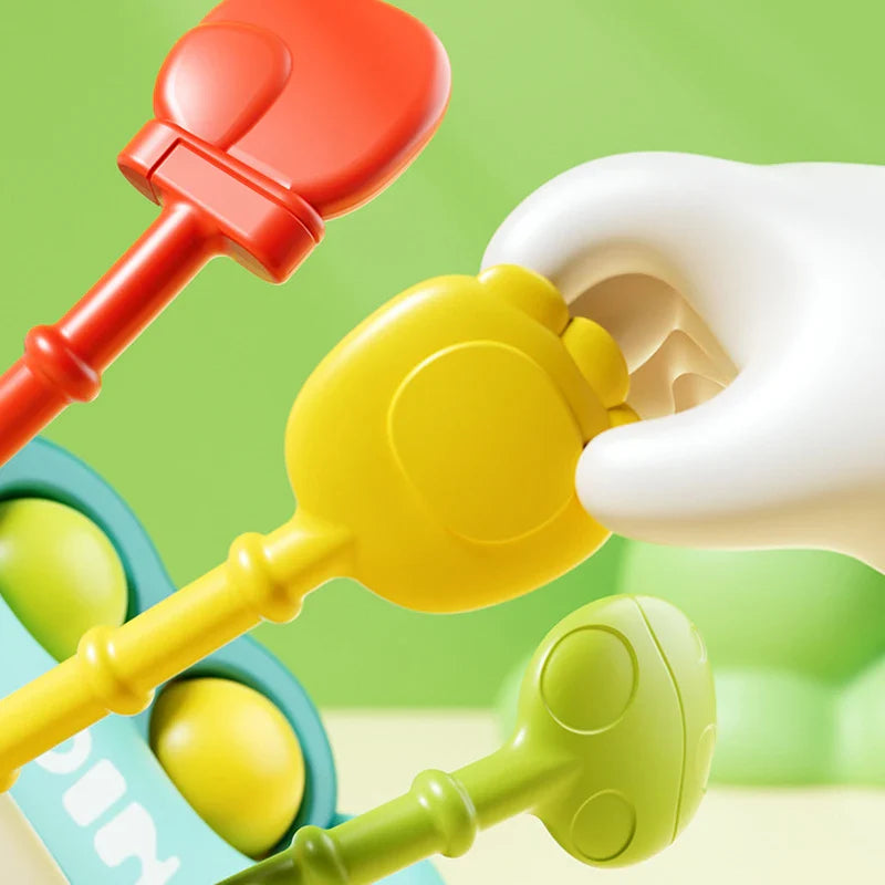 Close-up of a yellow pull-cord end beside red and green cords on the dinosaur toy