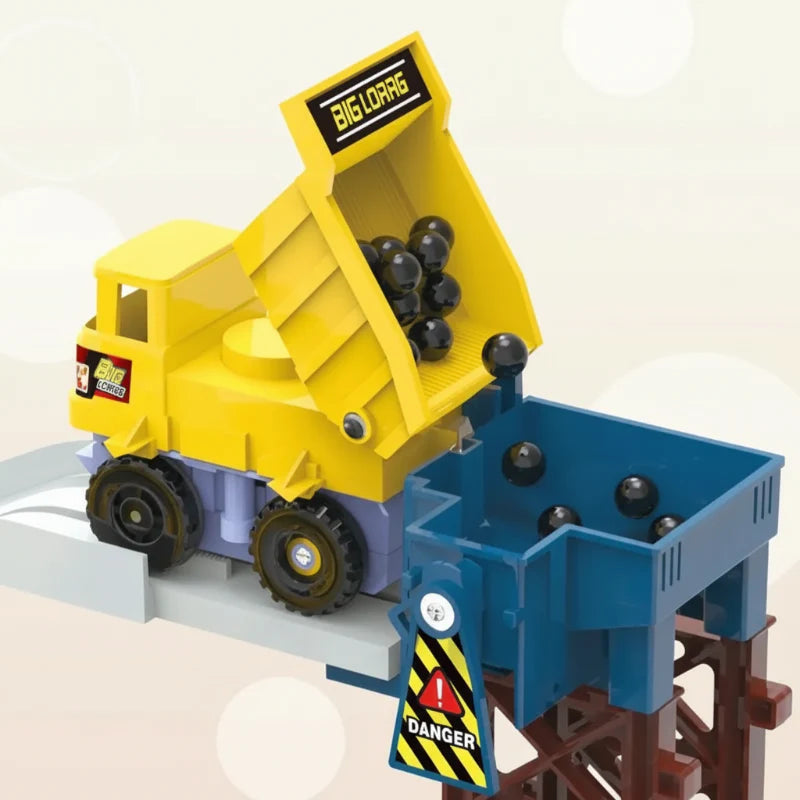 Yellow dump truck tipping black play balls into a blue hopper