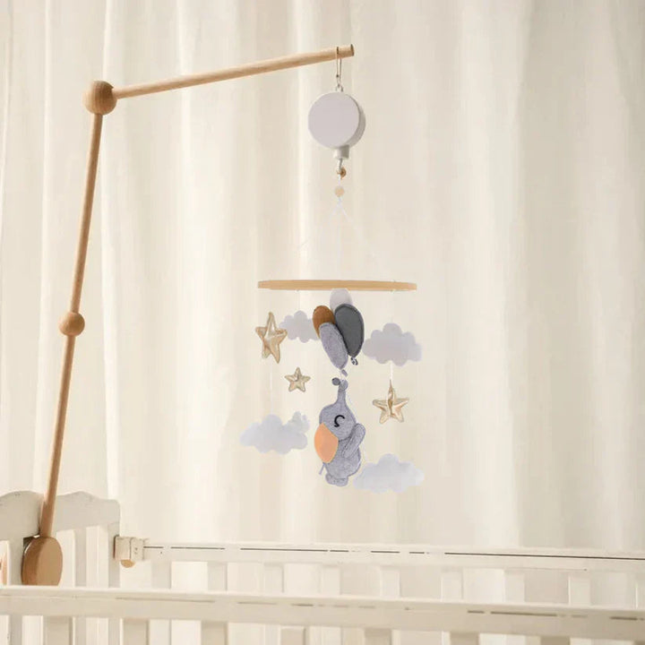 Elephant-and-balloon baby mobile hanging from a wooden mounting arm above a white crib