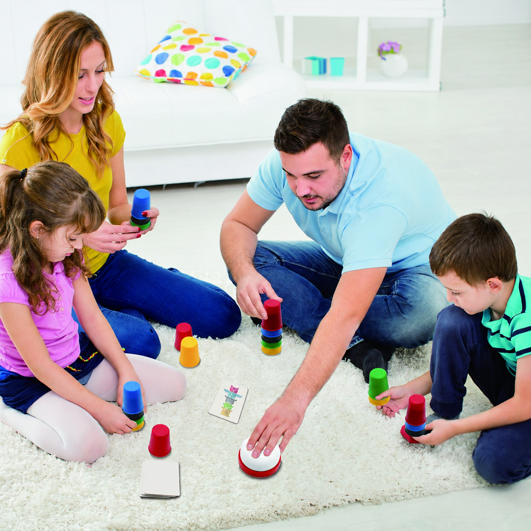 Two adults and two children playing the cup-stacking game on a rug