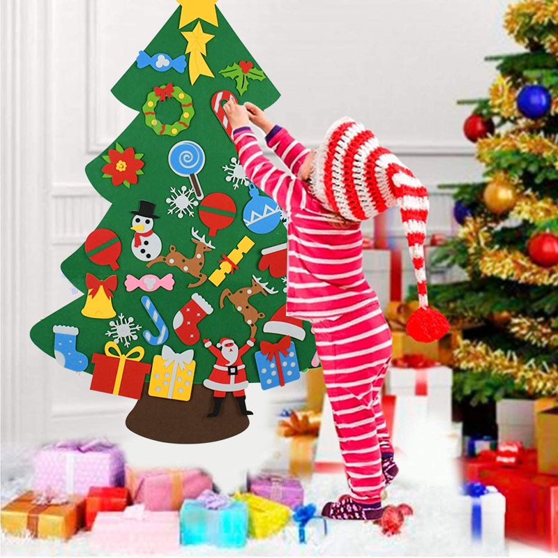 Child in red-and-white pajamas arranging ornaments on a hanging felt Christmas tree