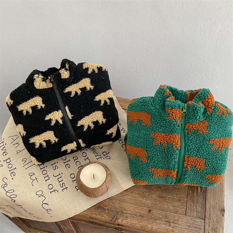 Folded black and green bear-print fleece jackets on a wooden table
