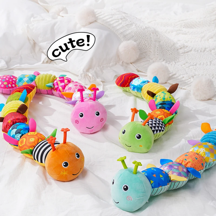 Pink, green, orange, and blue caterpillar rattles arranged on white bedding