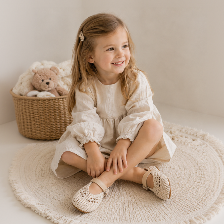 Girl wearing beige openwork Mary Jane flats with a cream dress