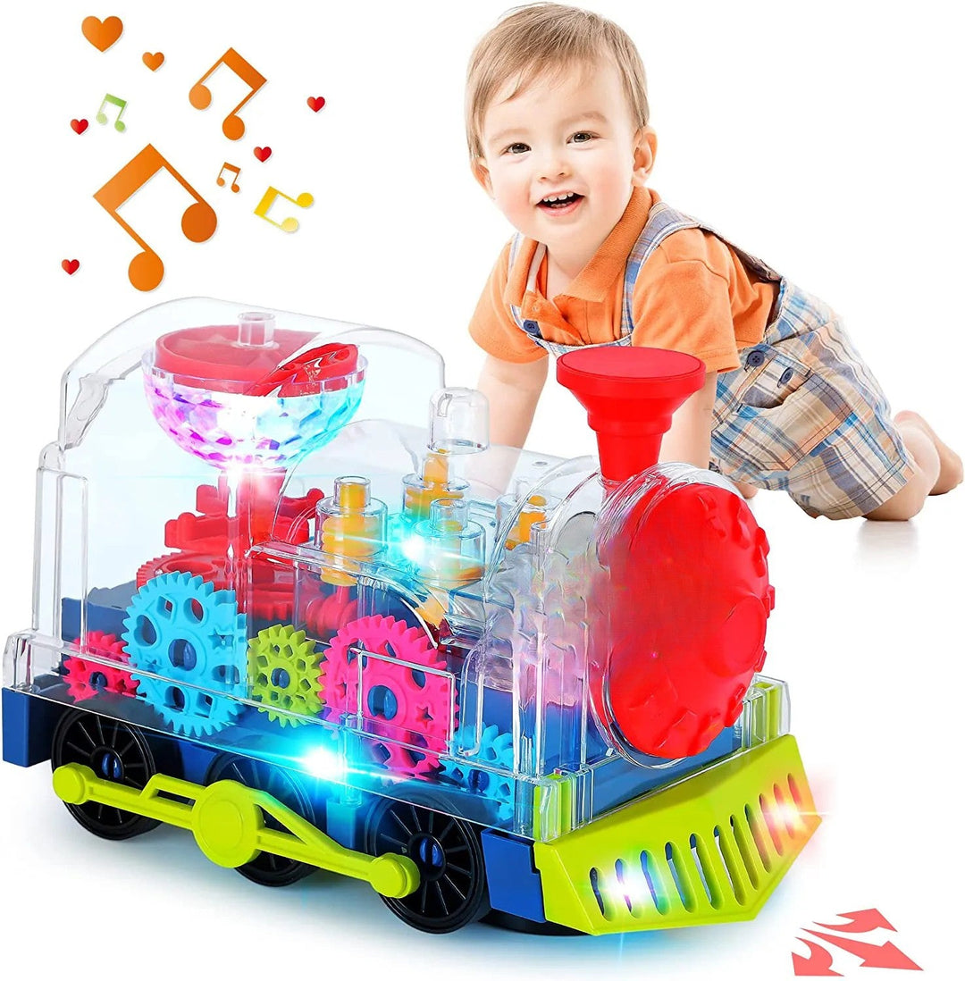 Clear toy train with glowing lights and colorful gears beside a child in an orange shirt.