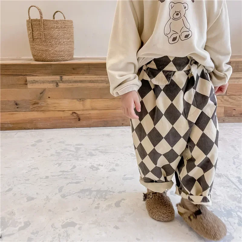 Child wearing gray argyle pants with rolled cuffs and a cream sweatshirt