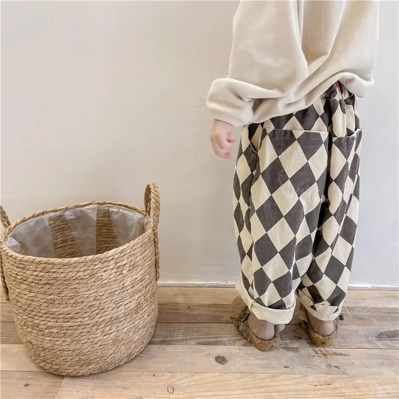 Side view of a child wearing gray argyle pants with a gathered waistband and rolled cuffs