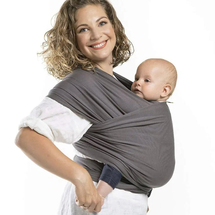 Gray baby wrap carrier with wide shoulder fabric, shown holding a baby in front.