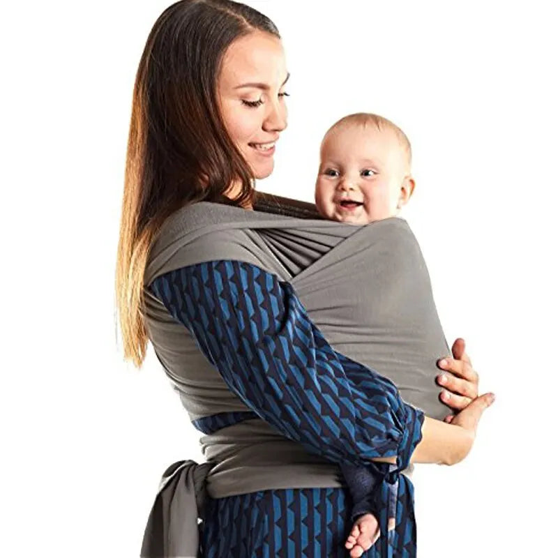 Side view of a gray baby wrap carrier with a waist tie and a baby carried in front.