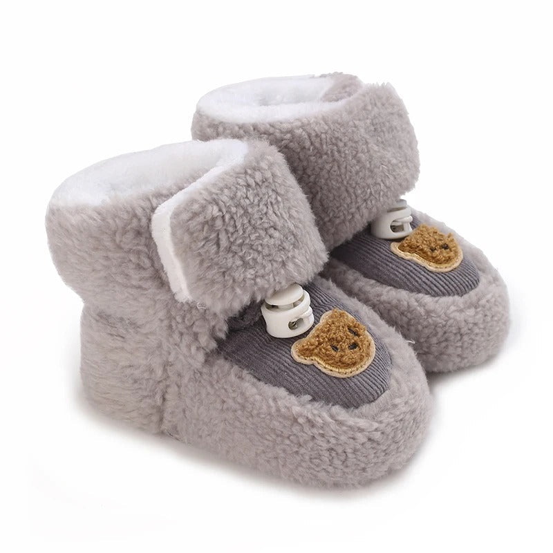 Gray plush baby shoes with bear patches and wide ankle closures.