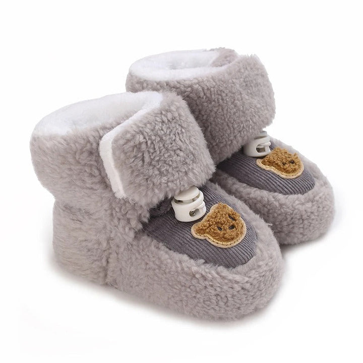 Gray plush baby shoes with bear patches and wide ankle closures.