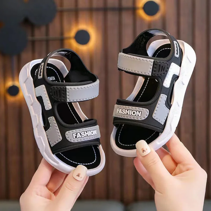 Gray and black sandals held upright to show the straps and open-toe design
