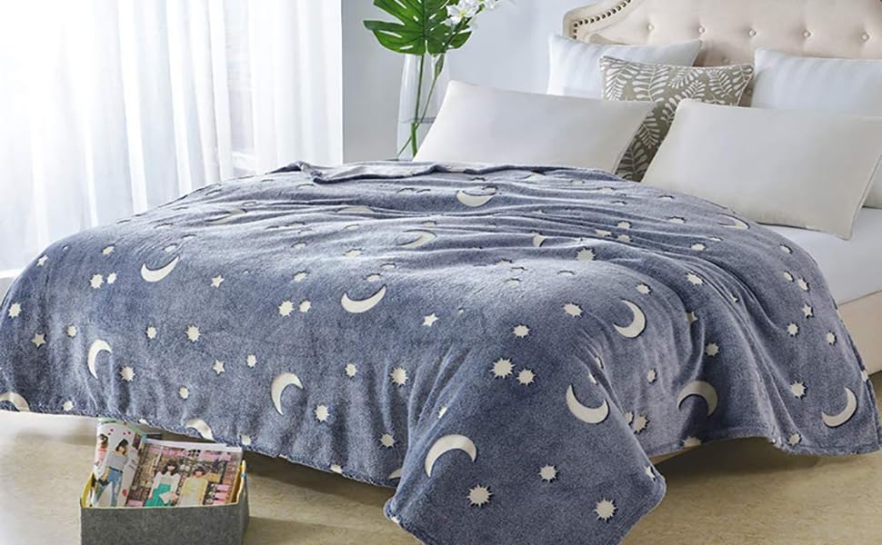Gray celestial-pattern blanket spread across a bed in a bright bedroom