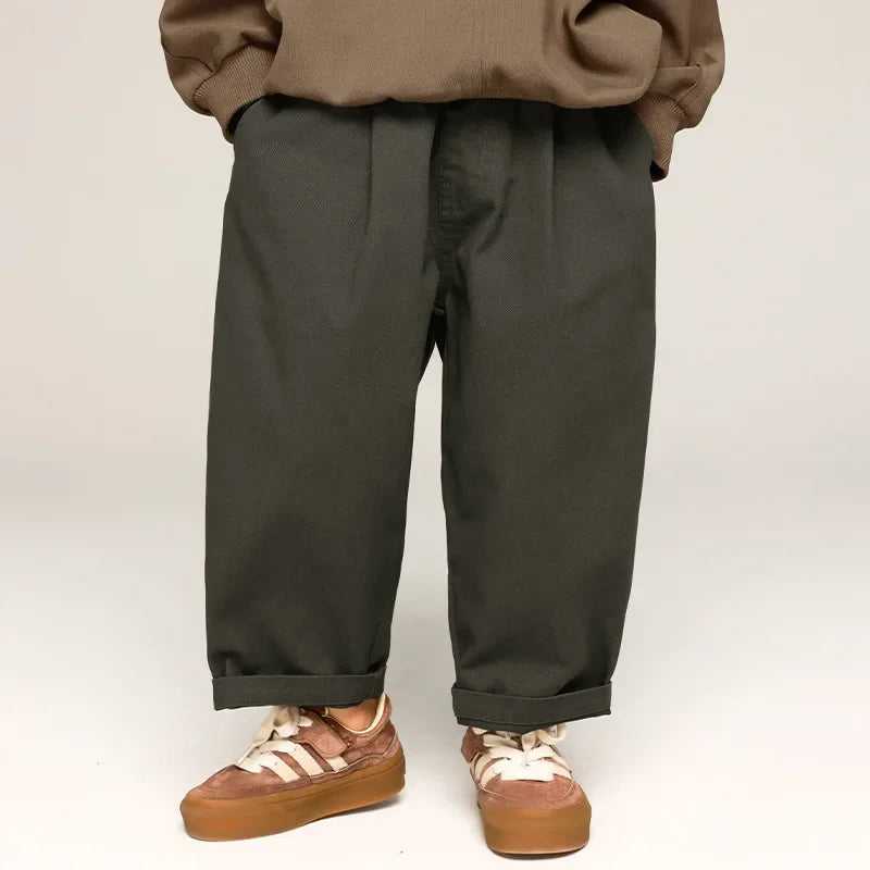 Gray kids' wide-leg pants with rolled cuffs, shown from the front with a brown sweatshirt and sneakers.