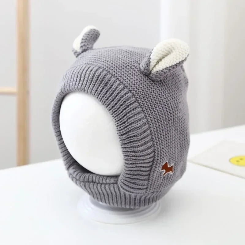 Gray knit balaclava with cream ears, a ribbed face opening, and a small animal patch