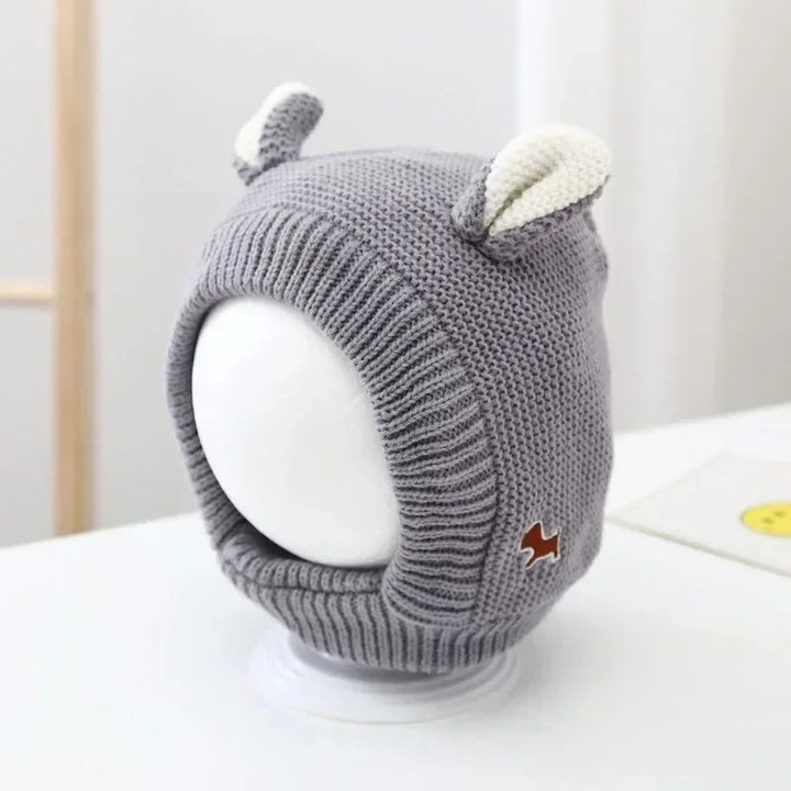 Gray knit balaclava with cream ears, a ribbed face opening, and a small animal patch