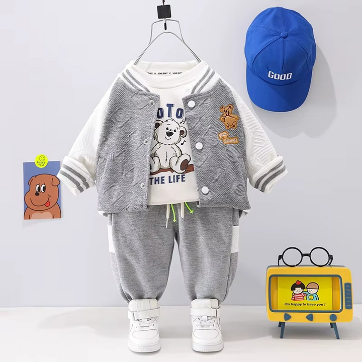 Gray-and-white varsity jacket with a graphic T-shirt and gray joggers, displayed beside a blue cap