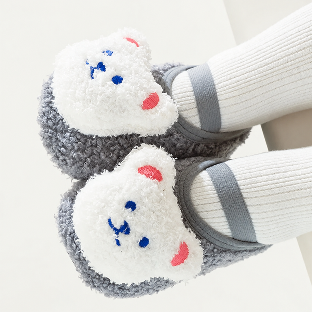 Gray baby slippers with white bear faces worn over white socks