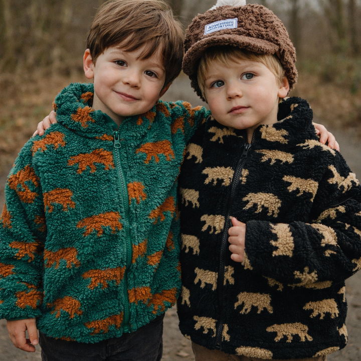 Two children wearing green and black bear-print fleece jackets outdoors