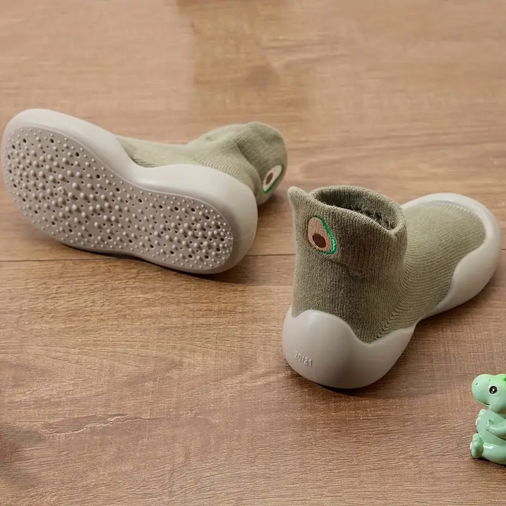 Green baby shoes showing the textured outsole, sock-style upper, and avocado detail