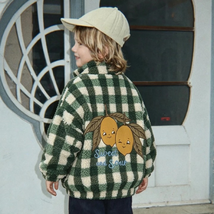 Child wearing a green checked fleece jacket with a lemon graphic on the back