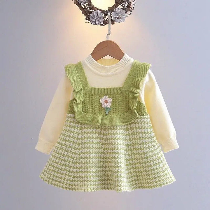 Green long-sleeve dress with ruffled trim, a small flower detail, and a houndstooth skirt