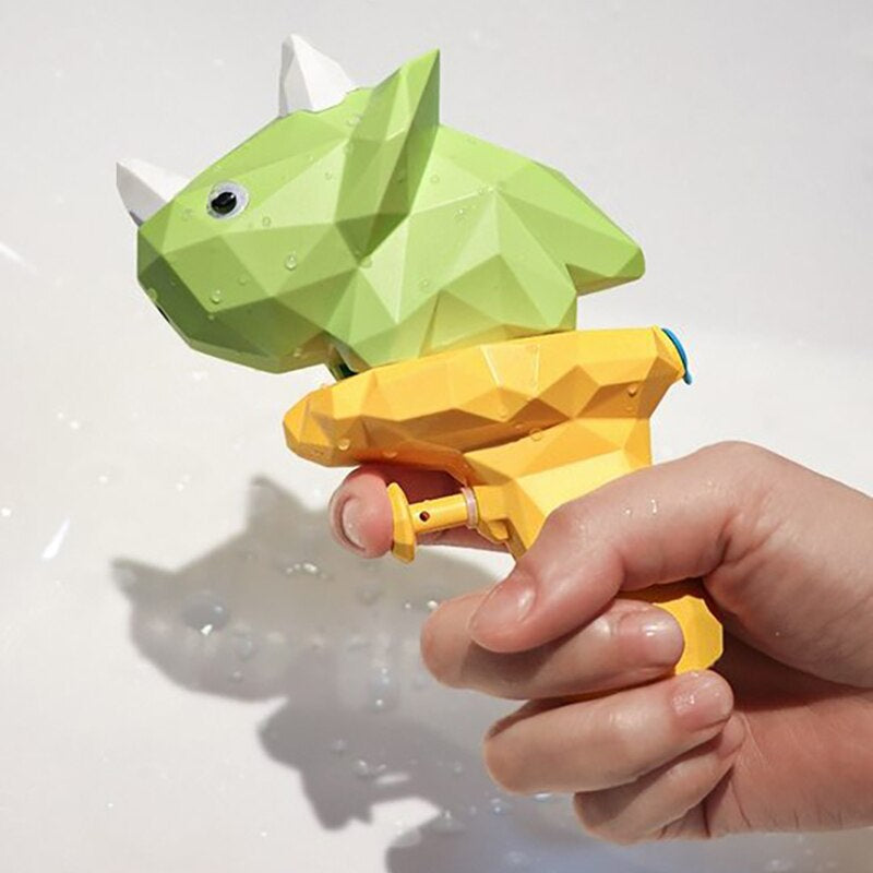 Hand holding a green horned dinosaur water gun with a yellow handle.