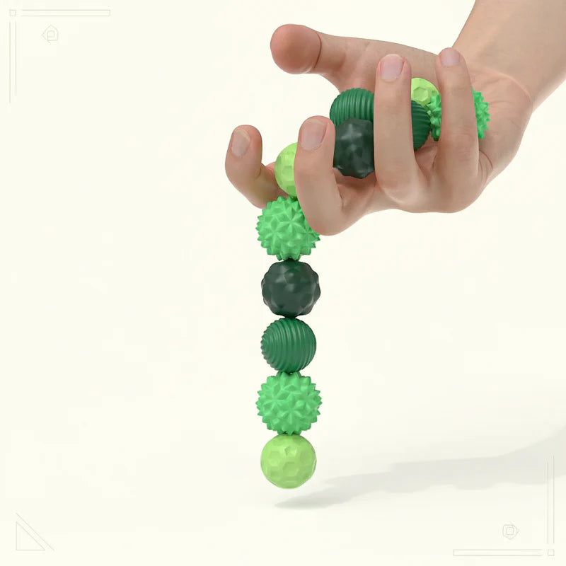 A hand holding a connected strand of green textured magnetic fidget beads