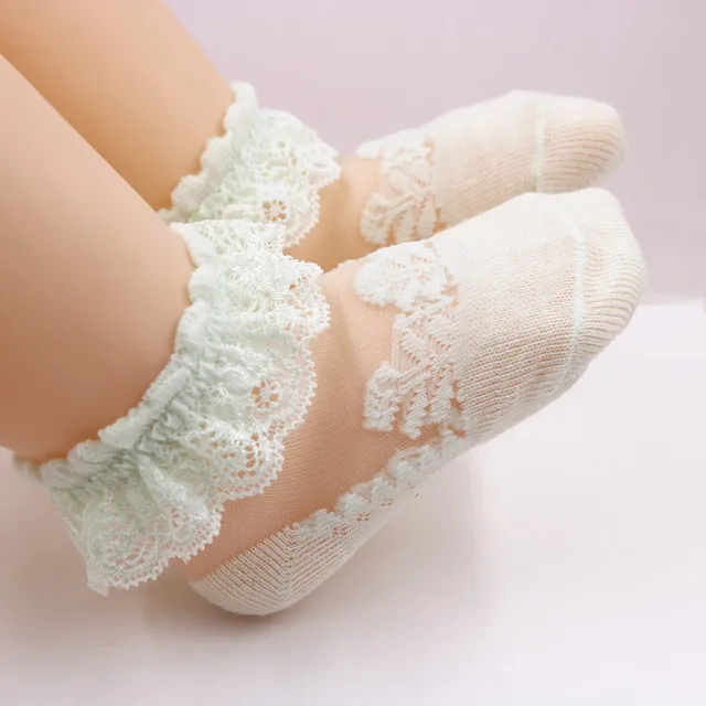 Pale green lace baby socks with ruffled cuffs and sheer mesh uppers.
