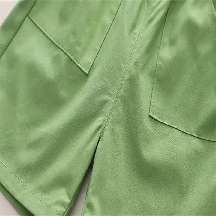 Close-up of the green shorts showing front pockets, stitching and folded hems