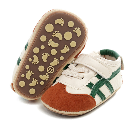 Cream and rust-colored baby sneakers with green stripes and footprint-patterned soles
