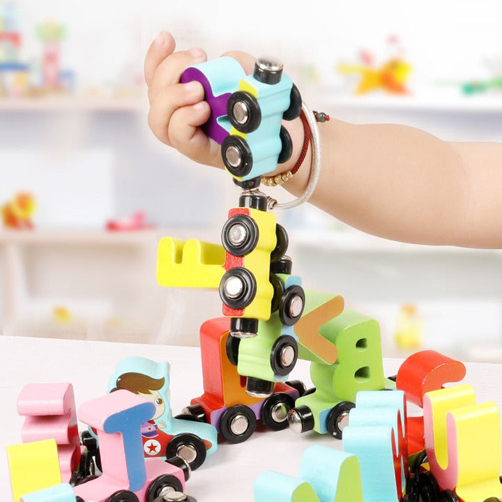 A hand lifts a chain of magnetically connected wooden train cars.
